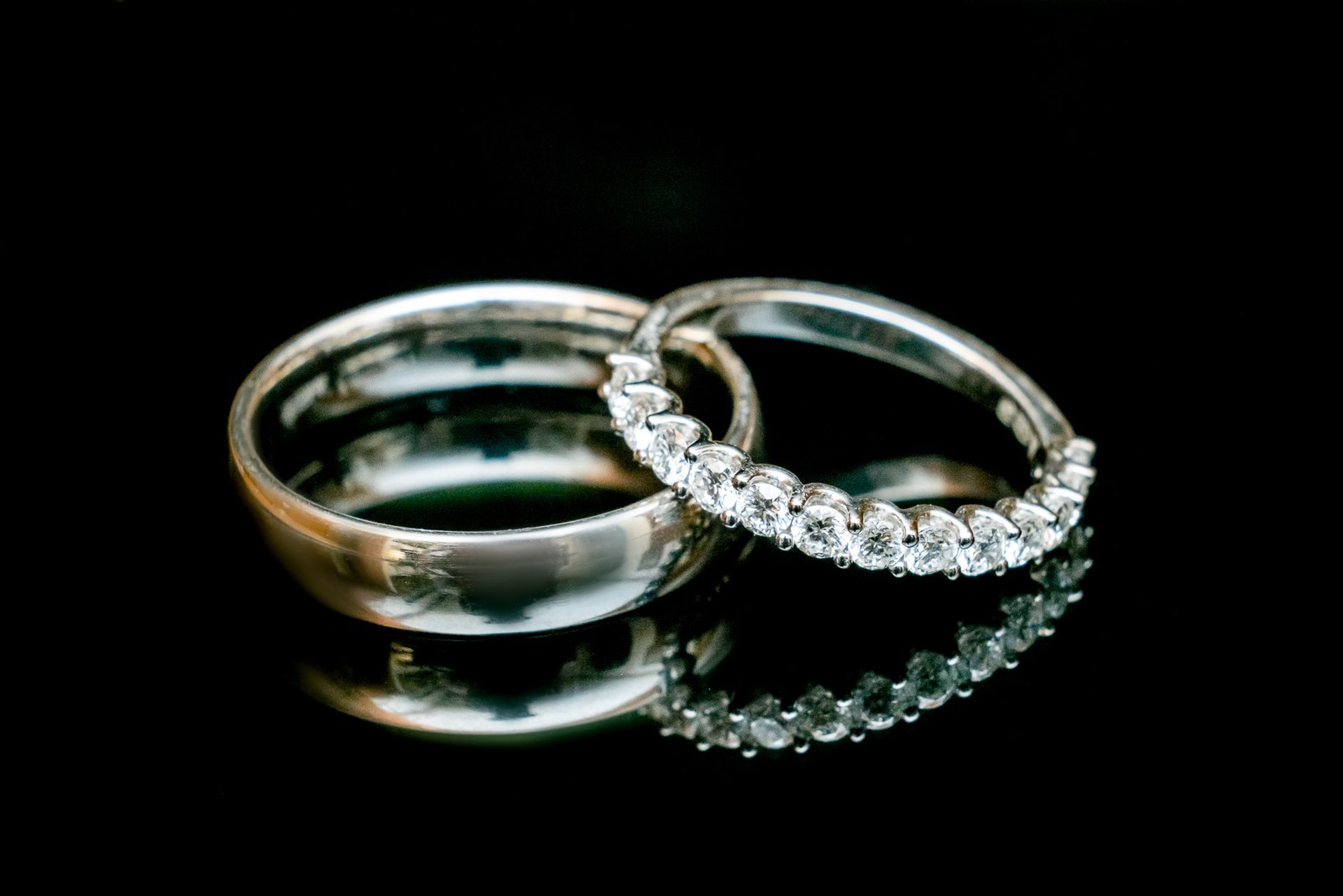The wedding rings, a plain band and a diamond eternity ring, on a black background
