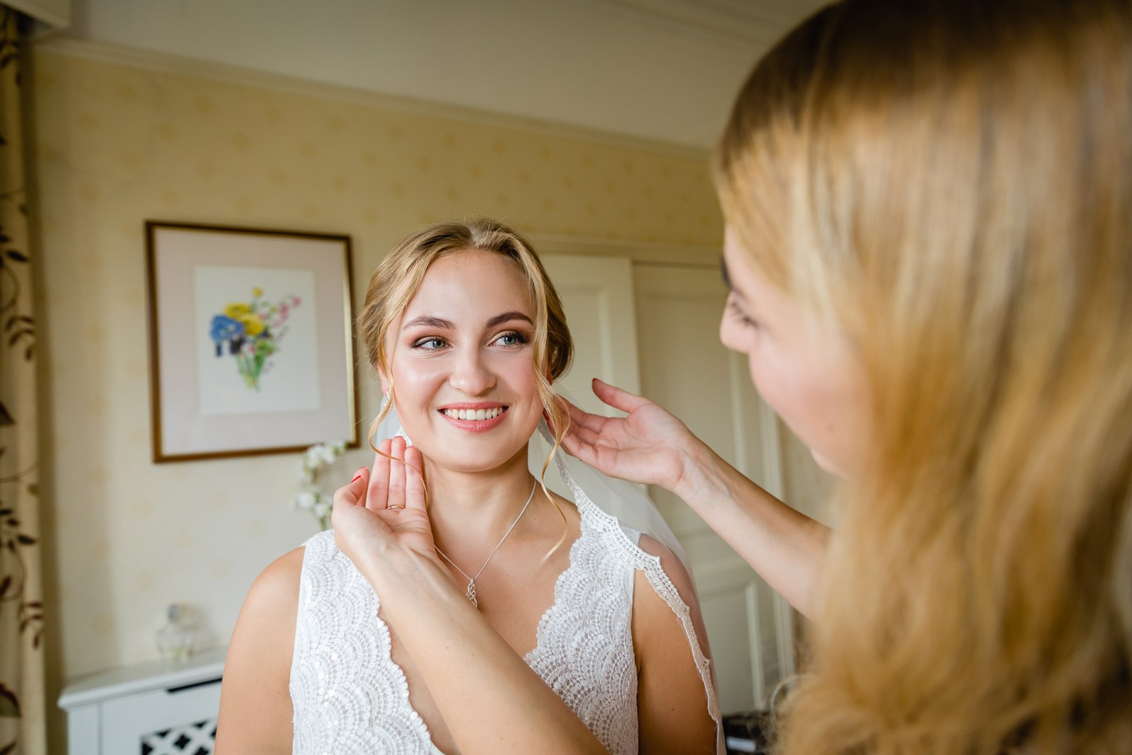 A woman adjusting the bride's hair as she smiles