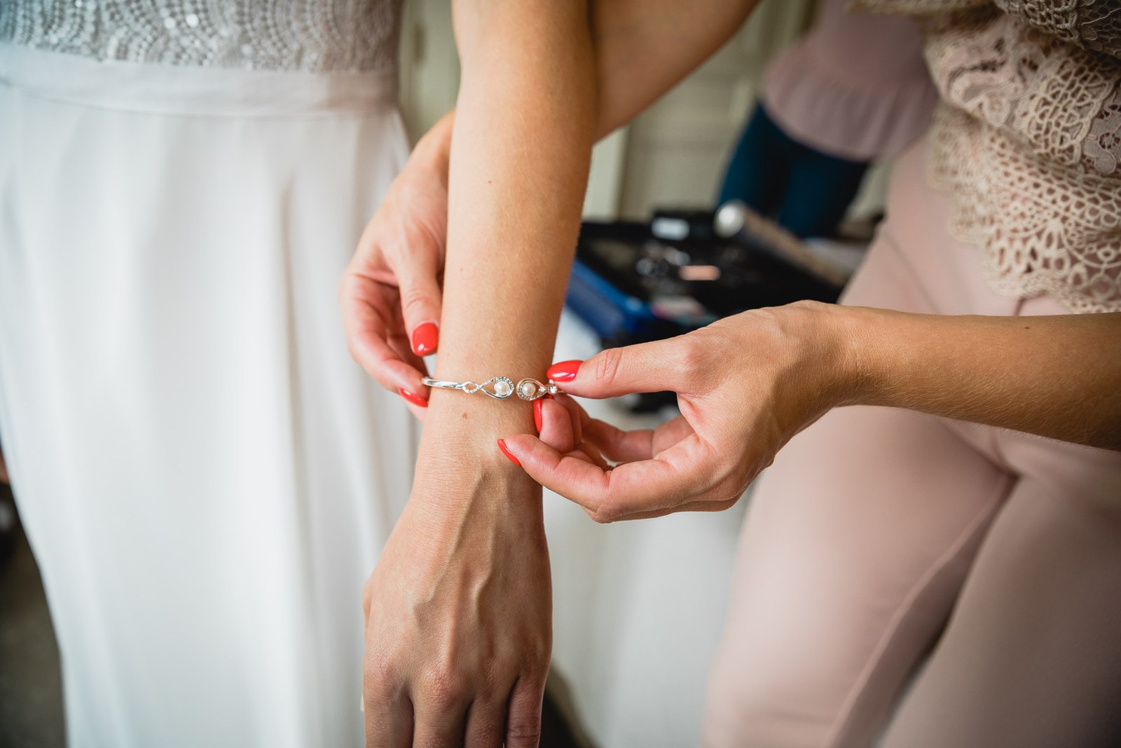 A delicate bracelet being fastened around the bride's wrist