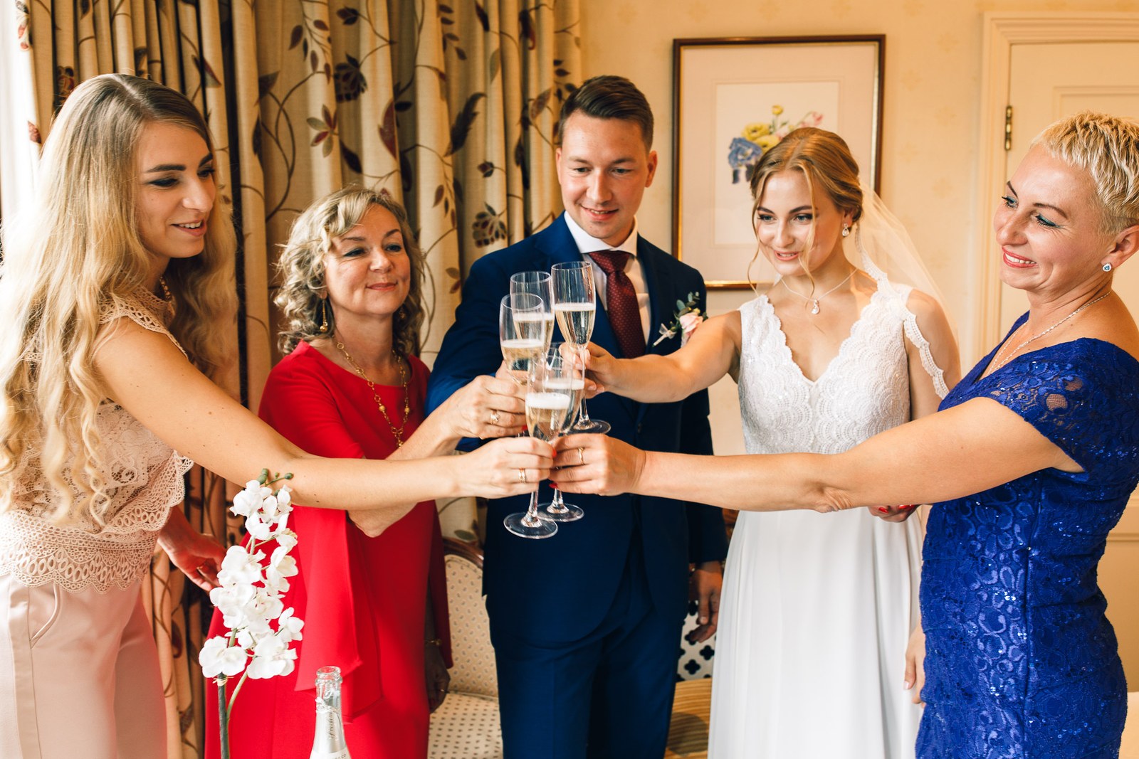 The bridal party toasting with prosecco around the groom in a blue suit