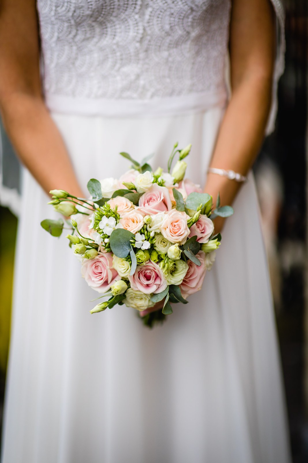 The bride holding a pink and cream rose bouquet against her gown