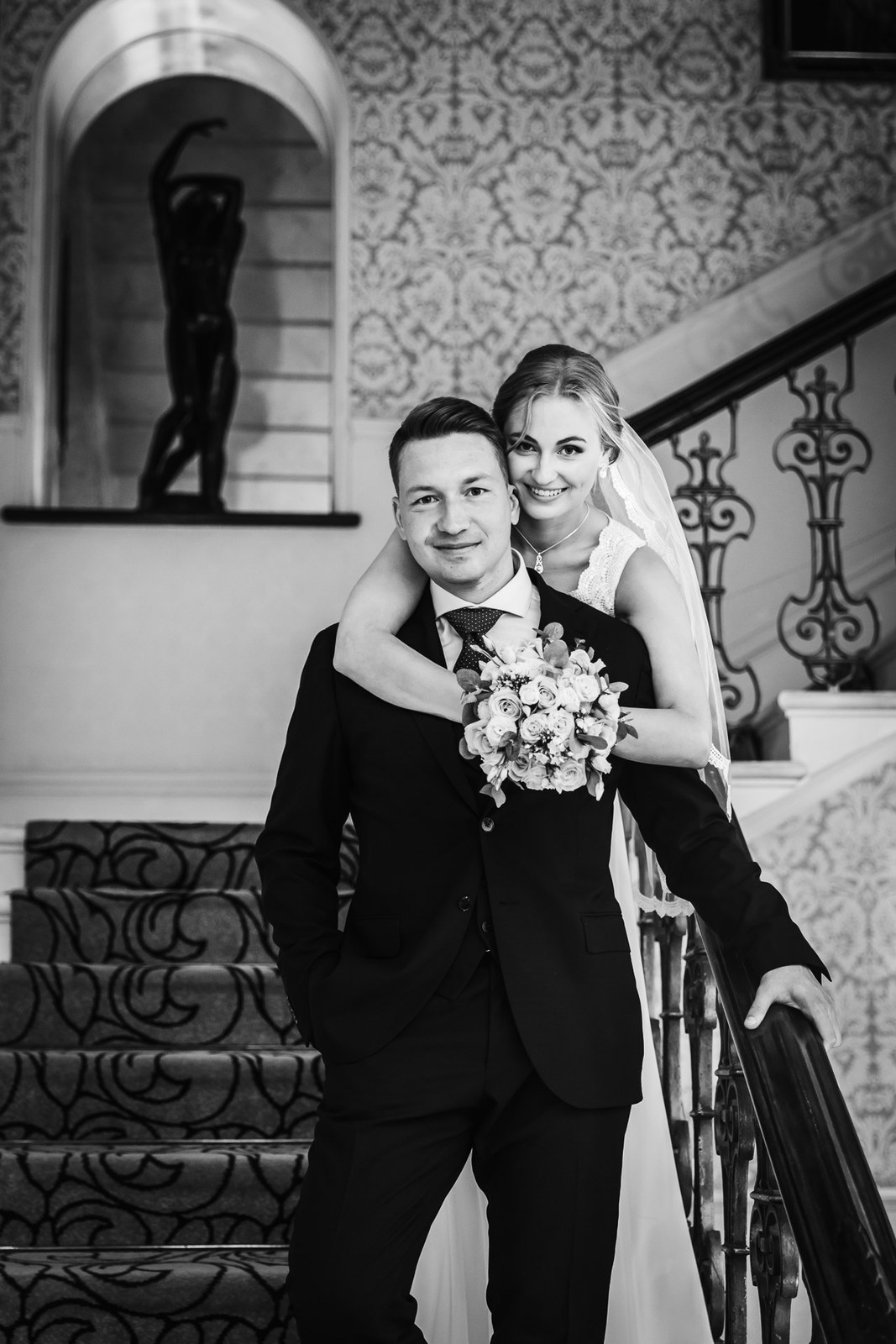 Black-and-white portrait of the couple embracing on the grand staircase