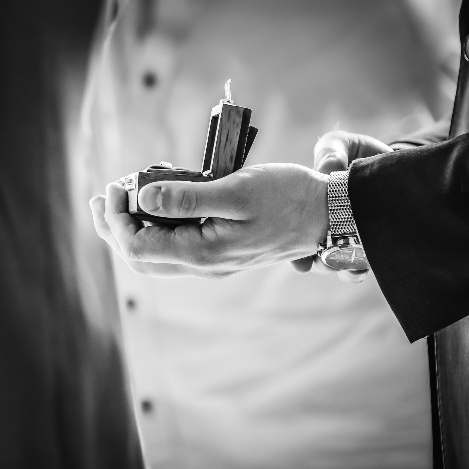 Black-and-white close-up of hands holding an open ring box