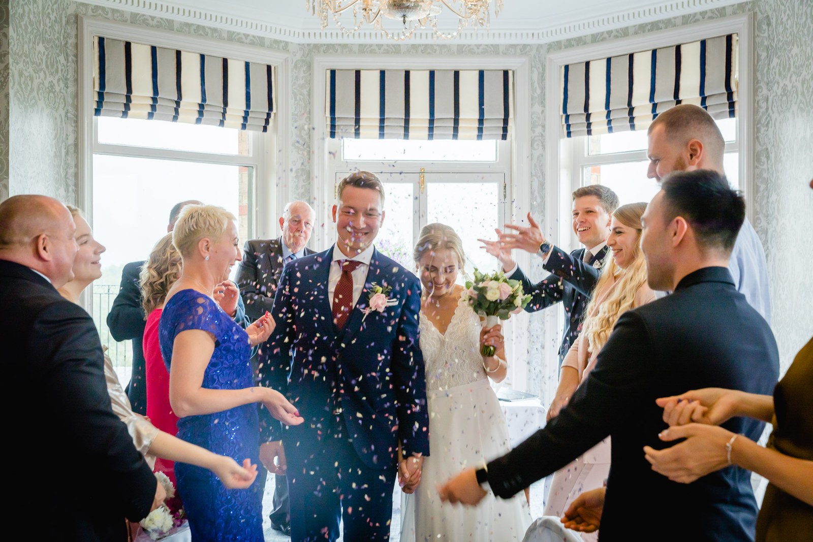 Guests showering the couple with confetti in the bay-windowed room