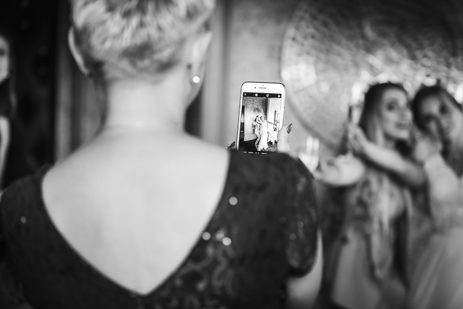 Black-and-white shot of a guest filming the couple on a phone