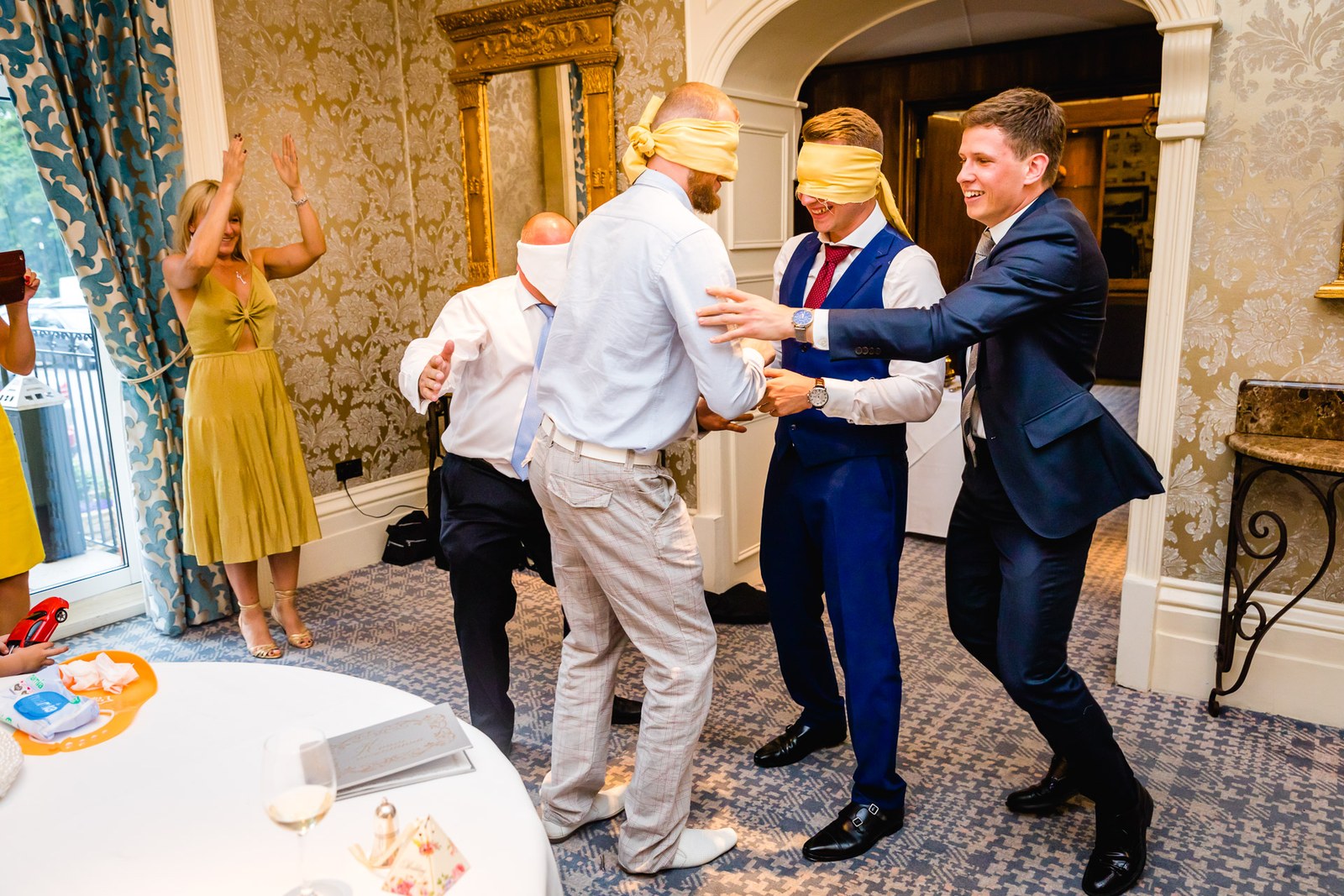 The blindfolded groom and guests playing a party game guided by others