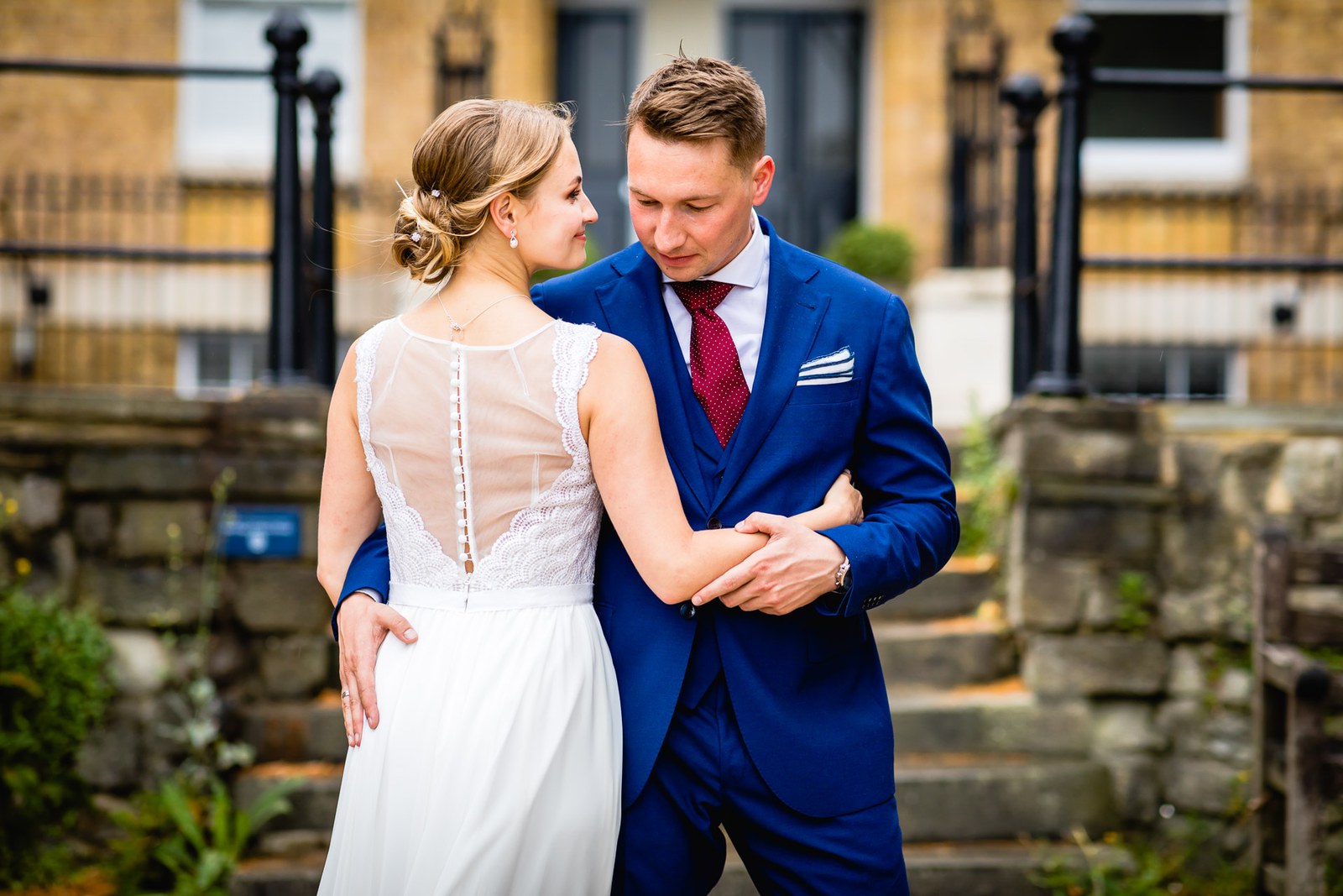 The couple walking arm in arm past the black railings of a brick townhouse