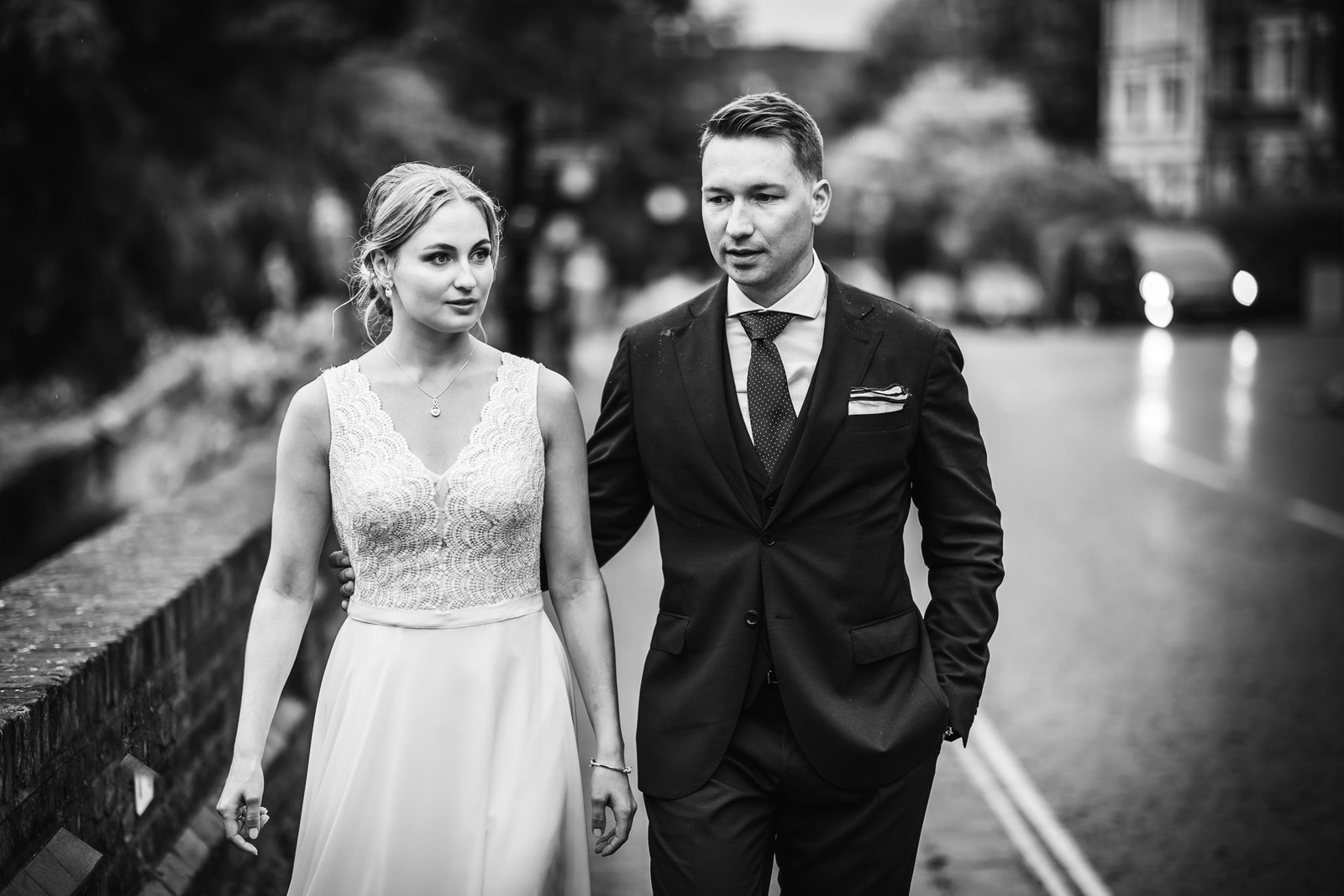 Black-and-white shot of the couple walking down a wet street