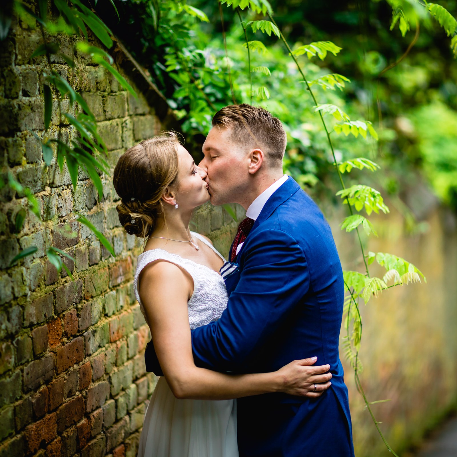The couple kissing against a weathered brick wall