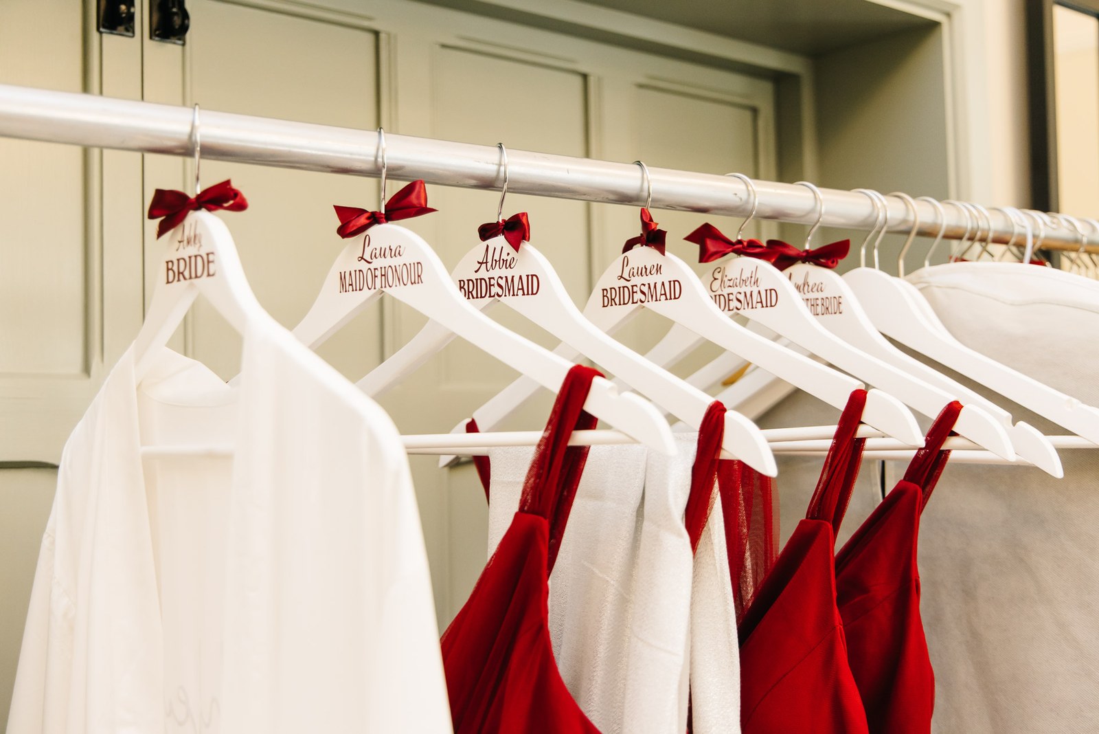 Personalised wedding hangers with red bows, labelled for the bride and bridesmaids
