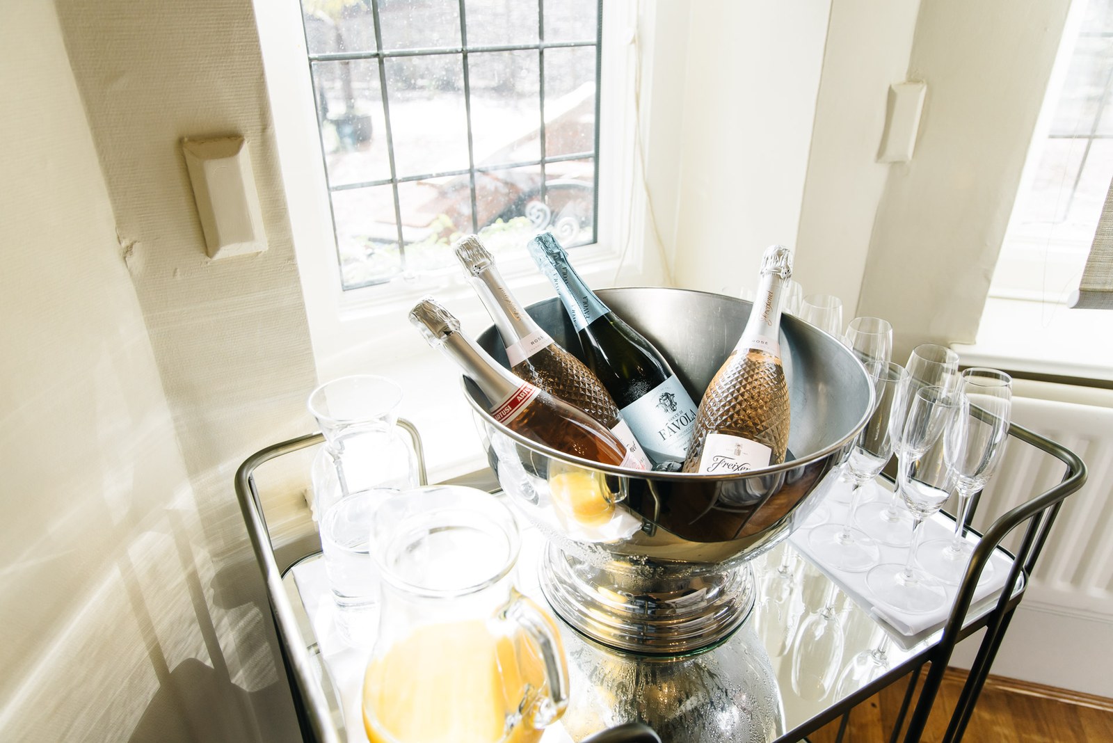 Prosecco chilling in a silver bucket with glasses on a drinks trolley by a window