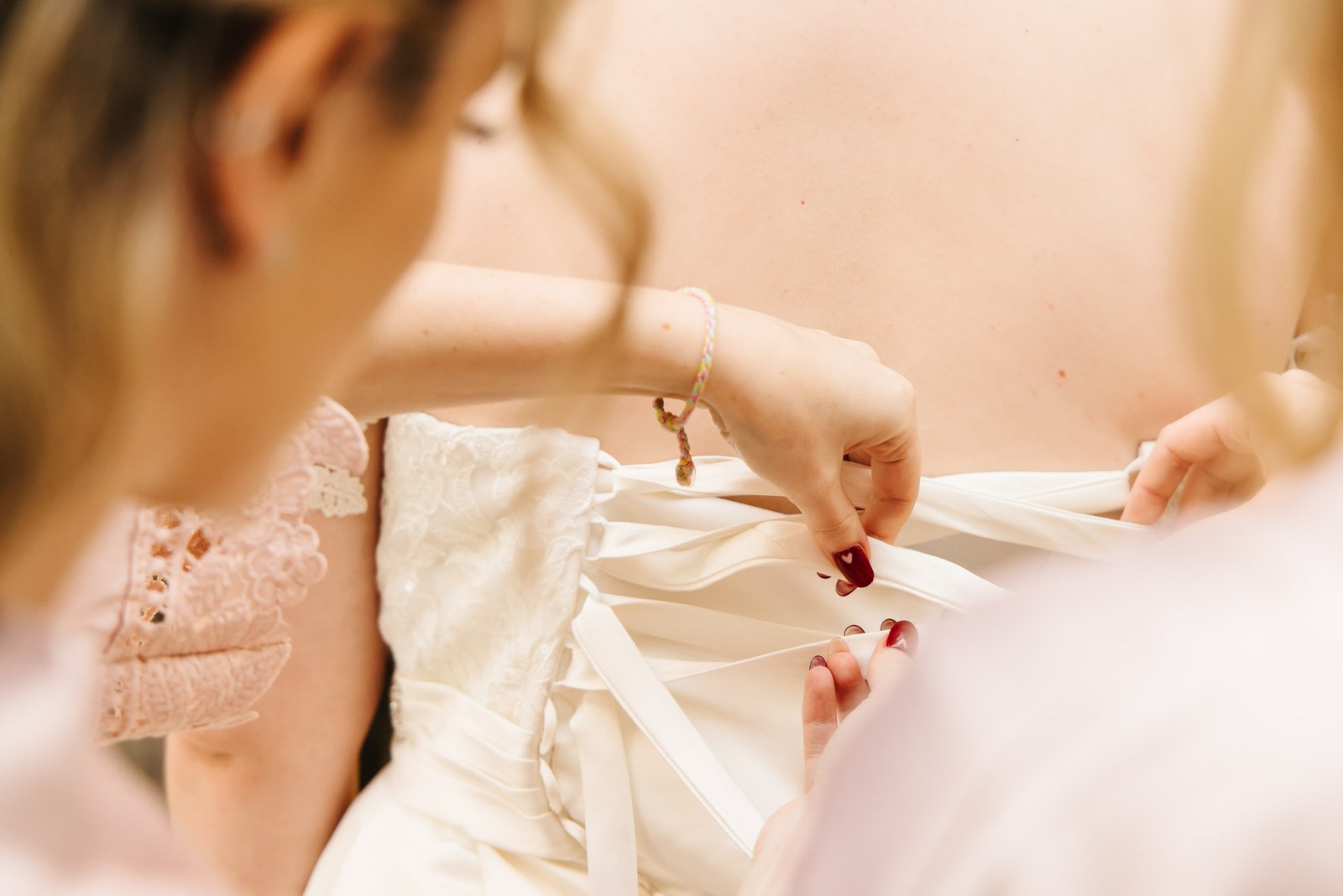 Close-up of hands lacing the back of the bride's corset gown