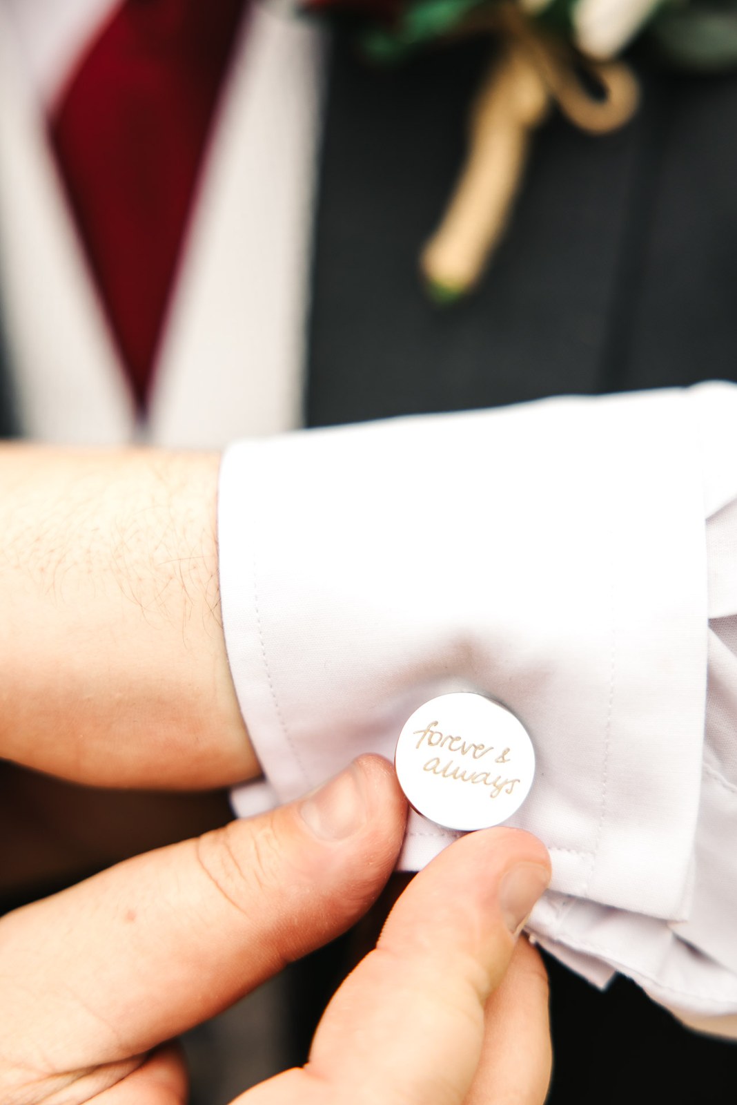 Close-up of a cufflink engraved 'forever and always' being fastened