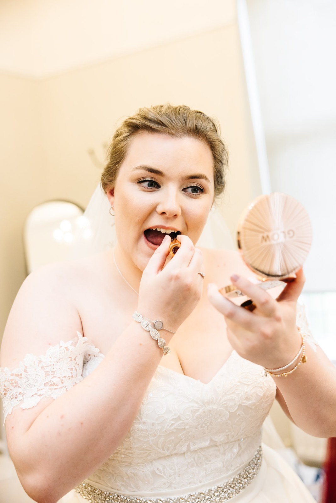 The bride applying lipstick with a compact mirror