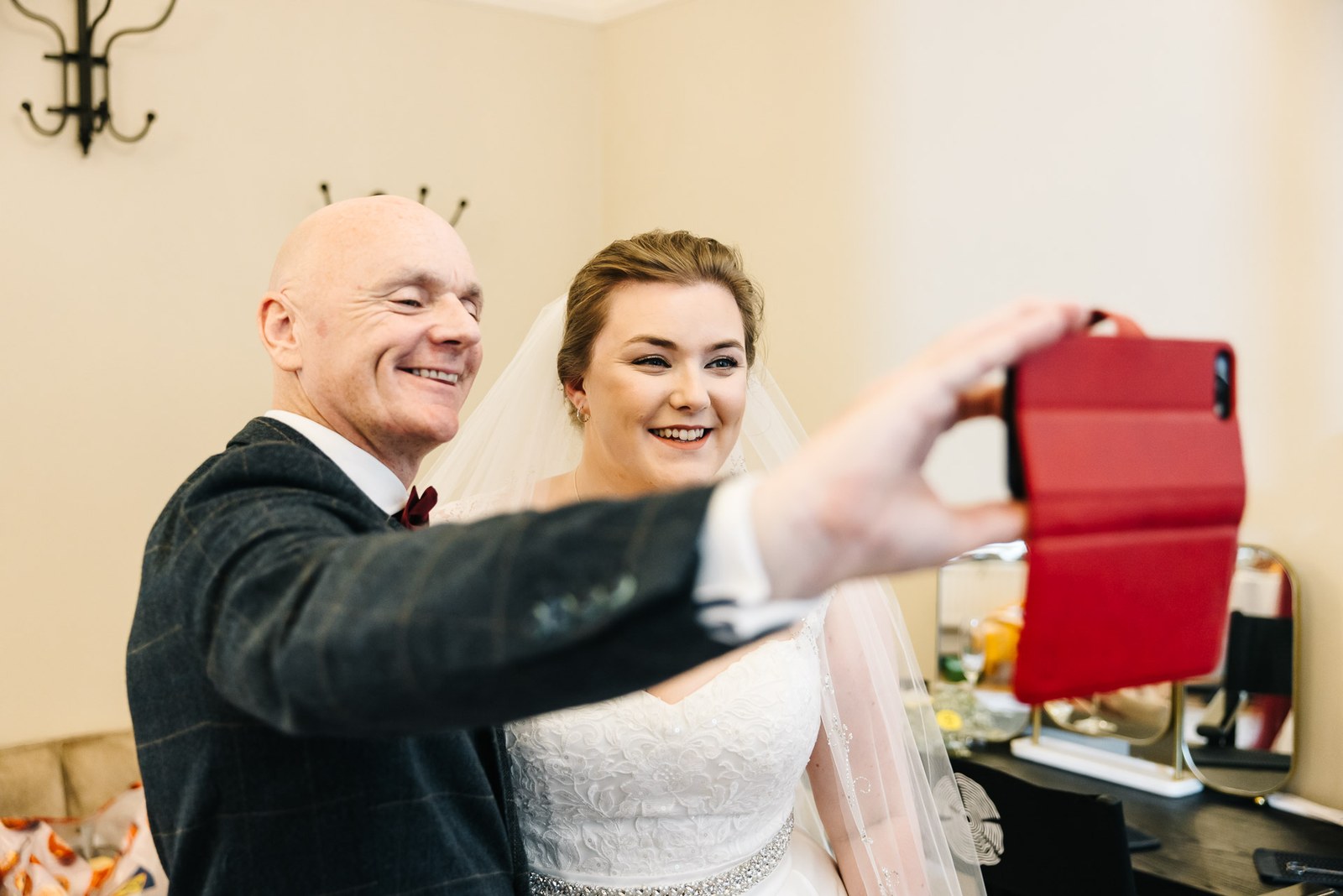 A father taking a selfie with the bride on a red phone