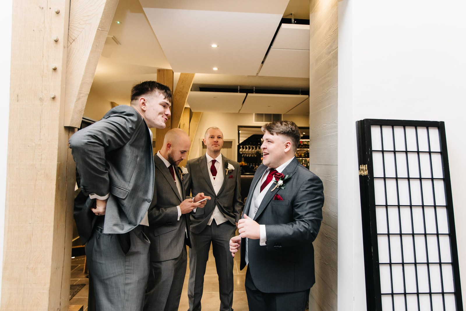 The groom chatting with his groomsmen by the timber posts of The Post Barn before the ceremony
