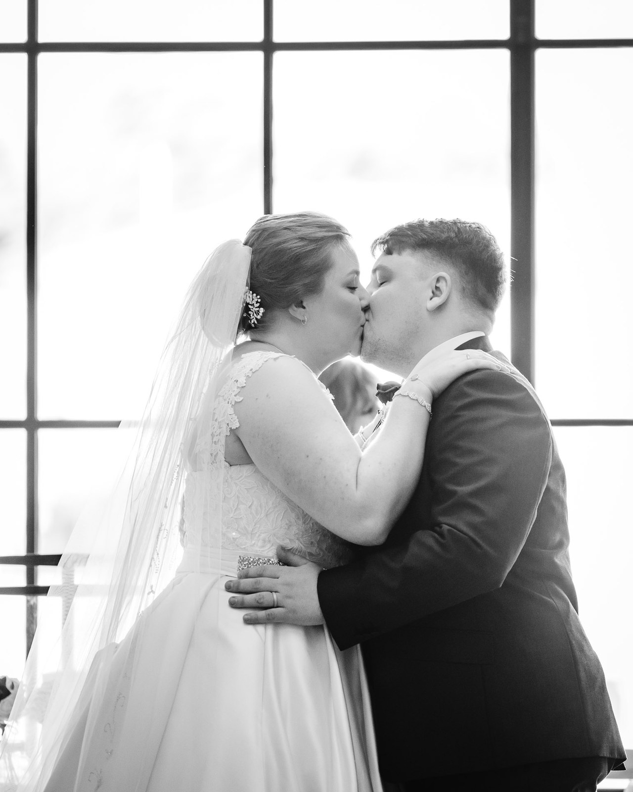 Black-and-white first kiss silhouetted against the tall window