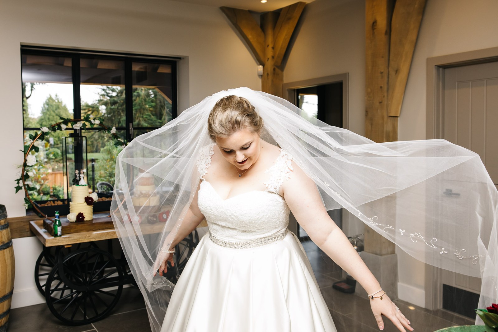 The bride twirling her veil in the barn beside a drinks cart