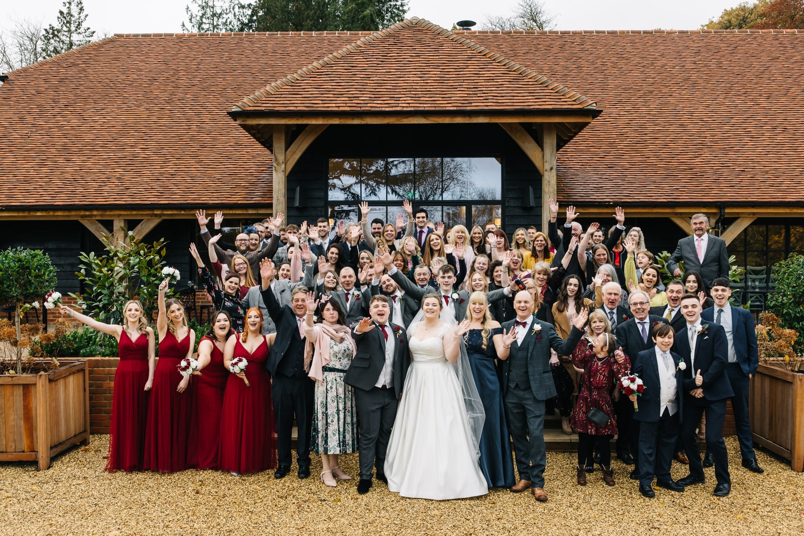 The full wedding party cheering outside the black-timbered barn at Snelsmore House