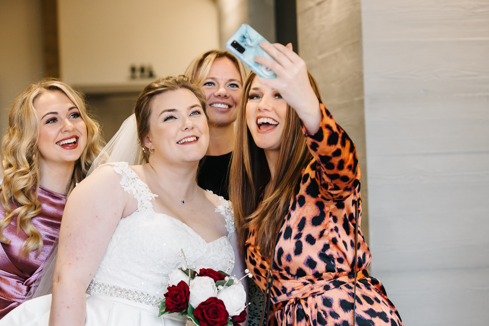 Friends crowding in for a selfie with the bride, who holds her bouquet