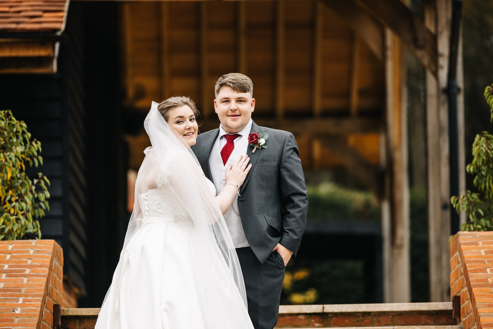 The couple posing on the steps outside The Post Barn amid autumn foliage