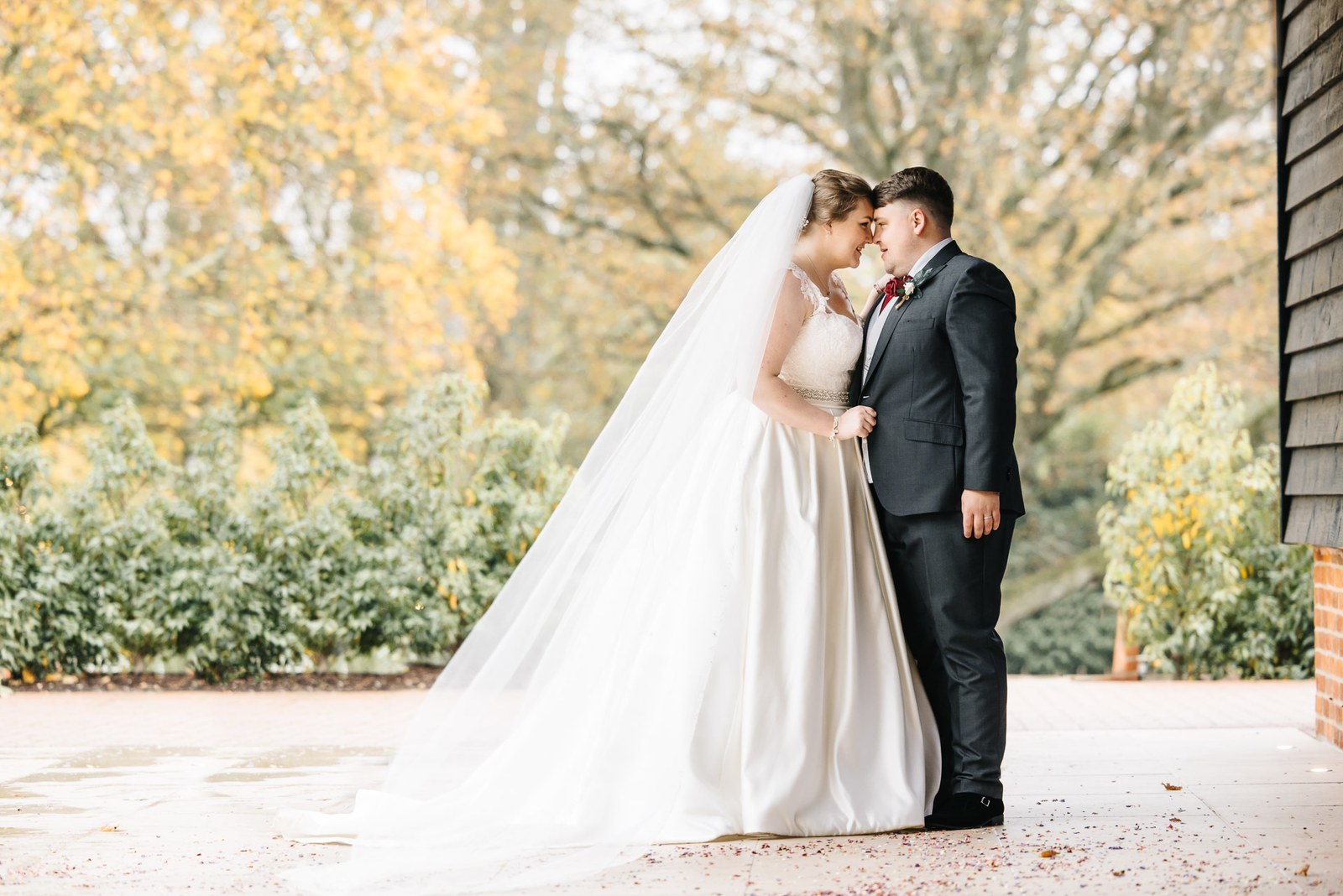 The couple resting their foreheads together in the autumn garden