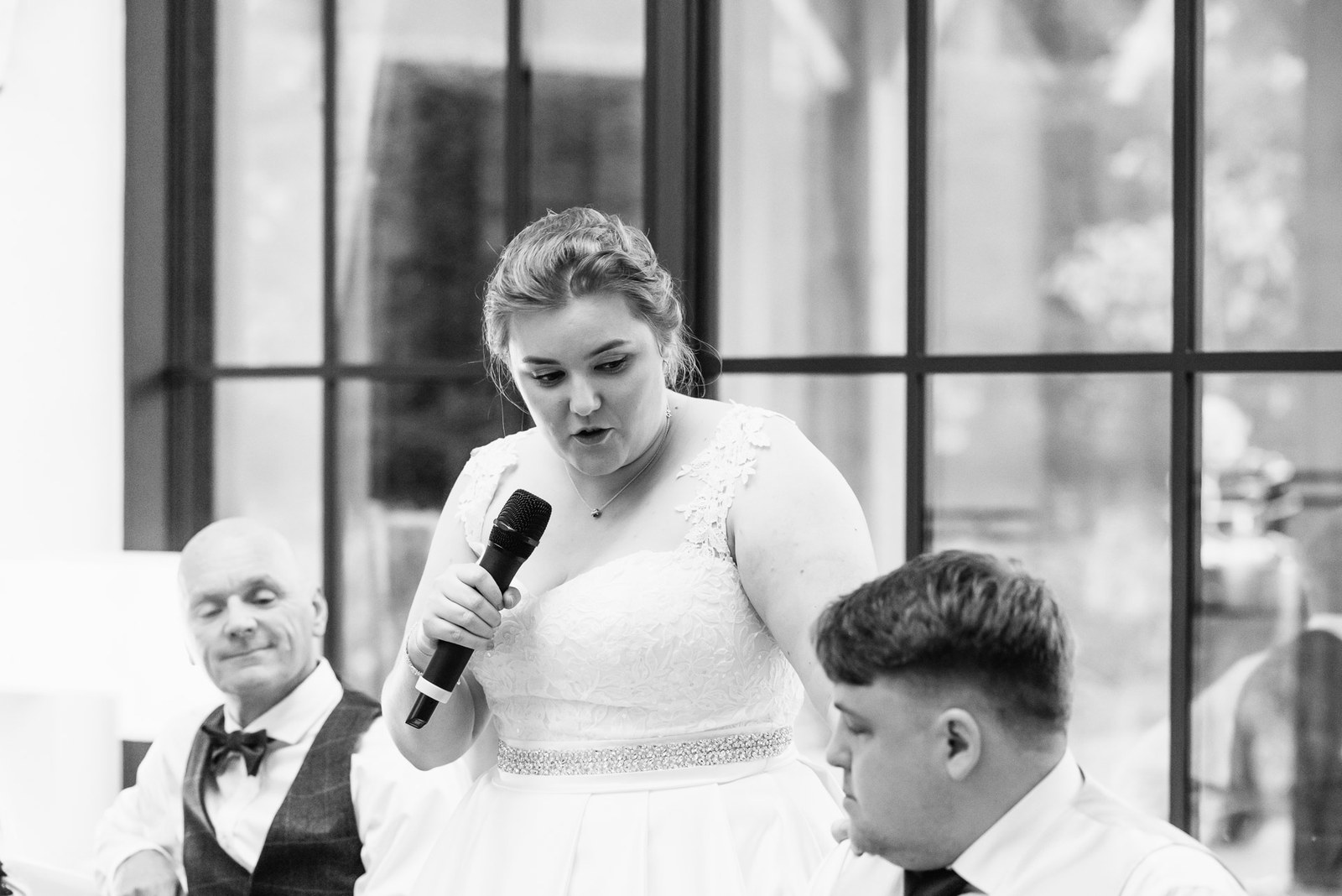 Black-and-white shot of the bride giving her speech into a microphone