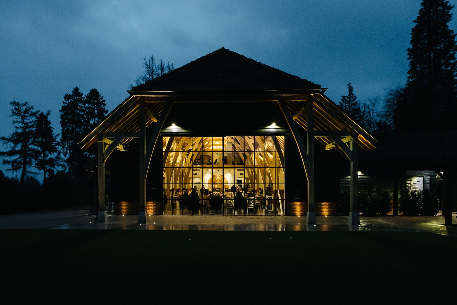 The Post Barn glowing at dusk, seen from the darkened grounds