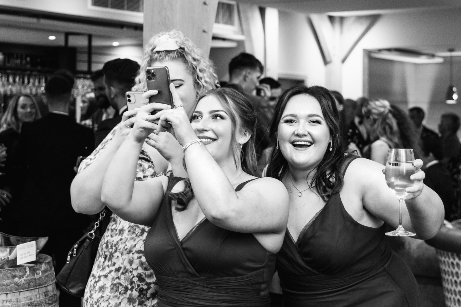 Black-and-white shot of bridesmaids raising a glass for a selfie