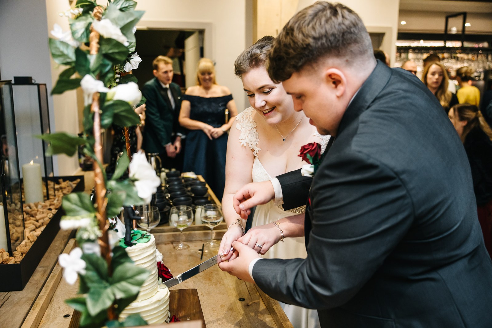 The couple cutting the greenery-trimmed wedding cake together