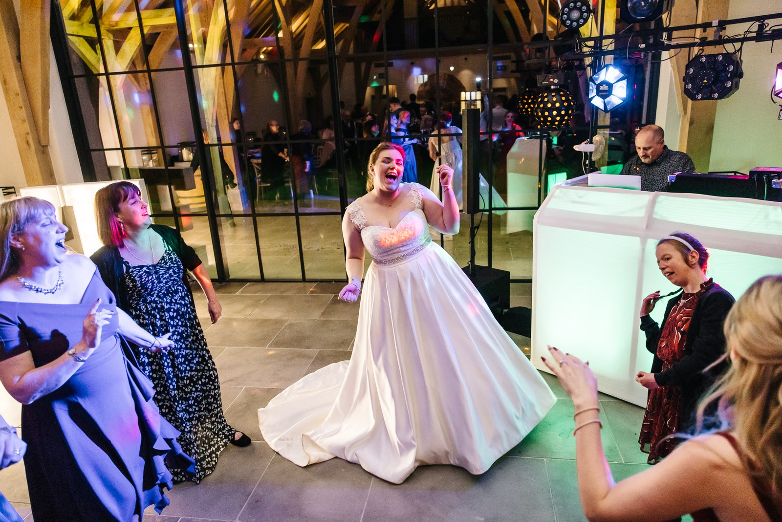 The bride dancing by the illuminated DJ booth as guests cheer
