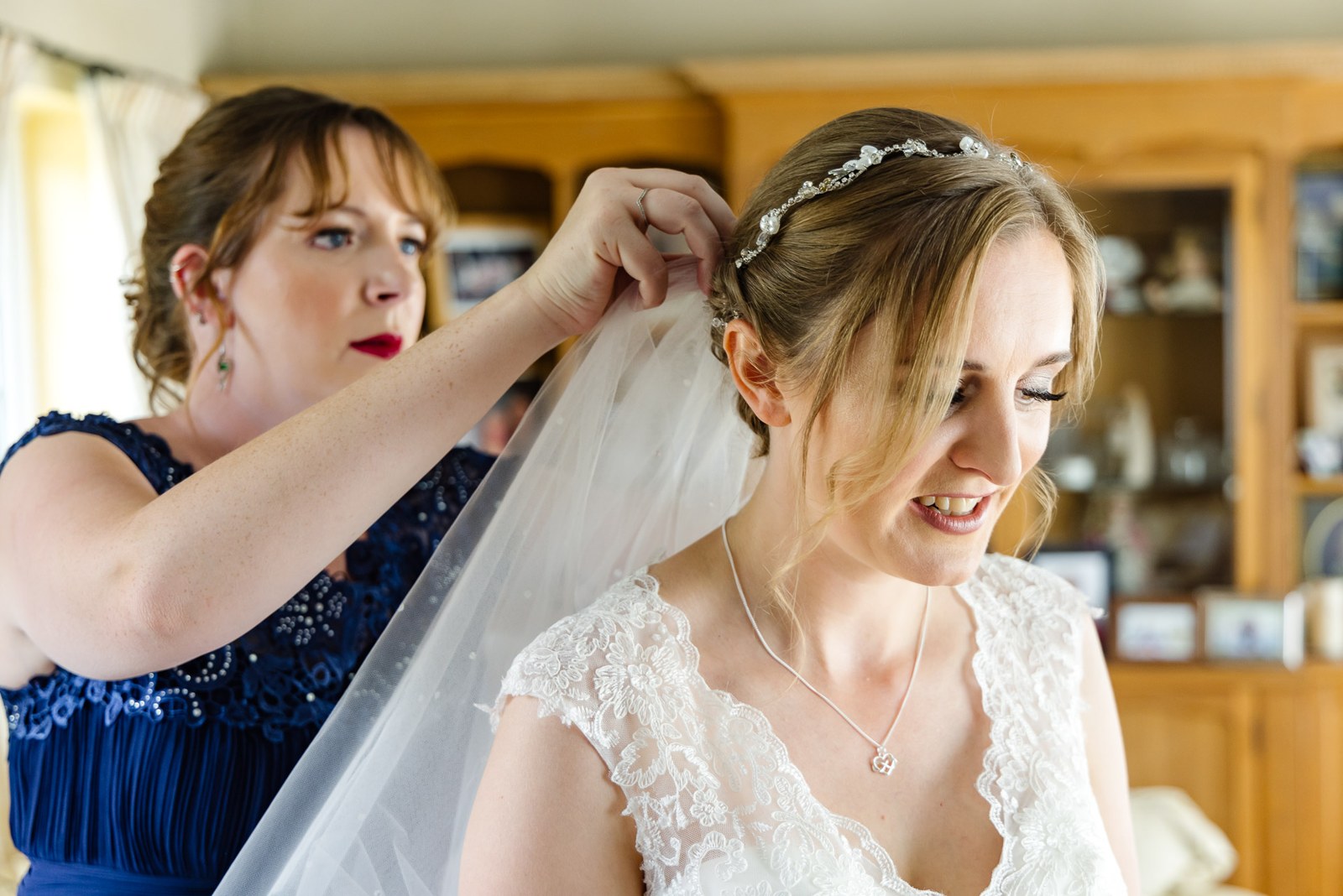 A bridesmaid fixes the veil into the bride's hair during preparations