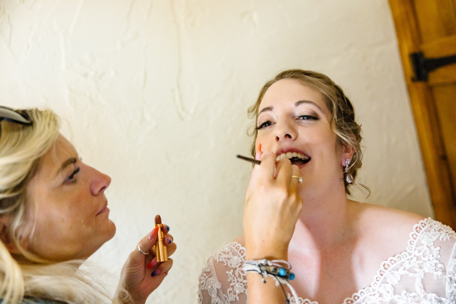 Make-up artist brushing colour onto a bride's lips before the ceremony