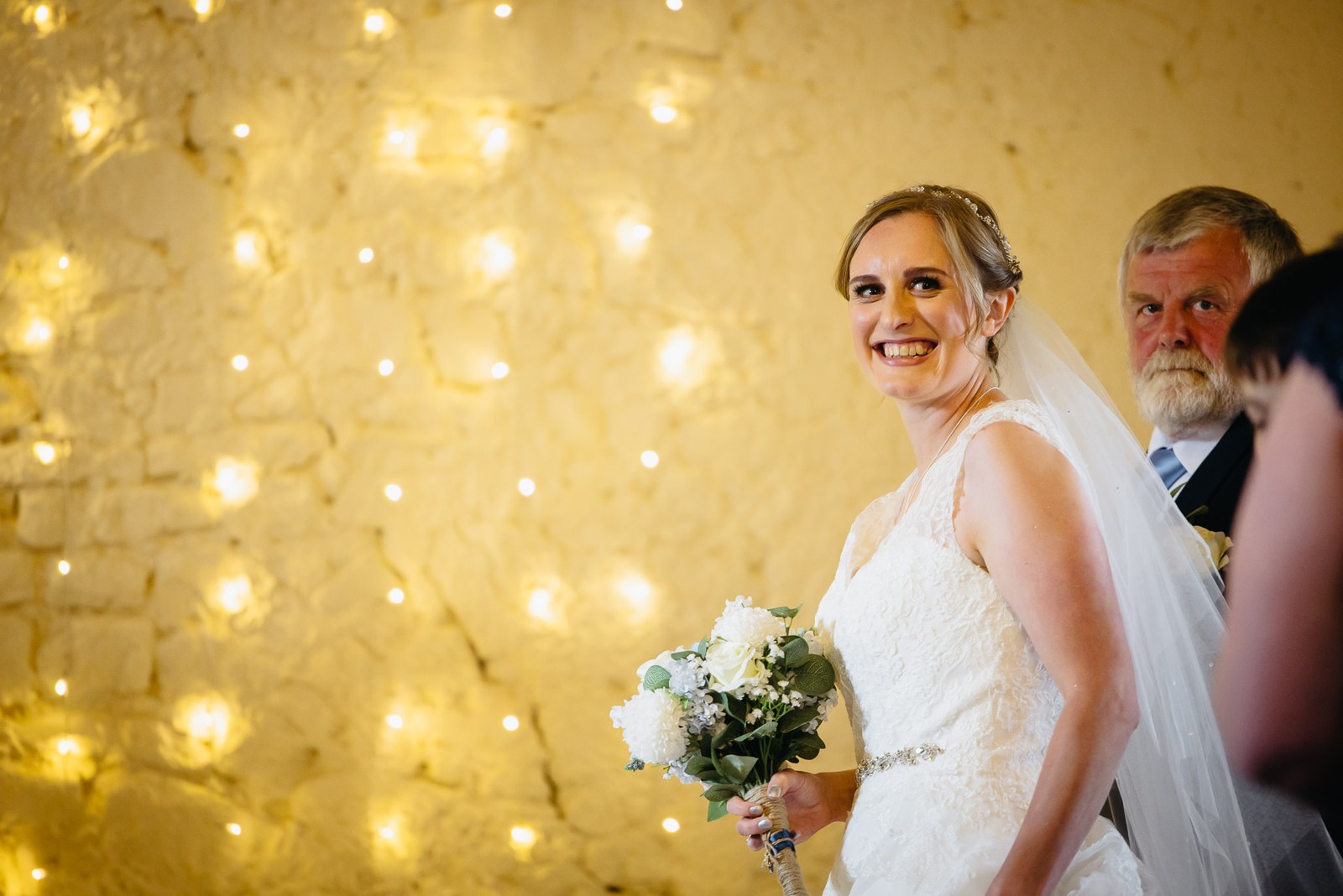 Bride framed against a shimmering curtain of fairy lights in the Slapton Manor barn