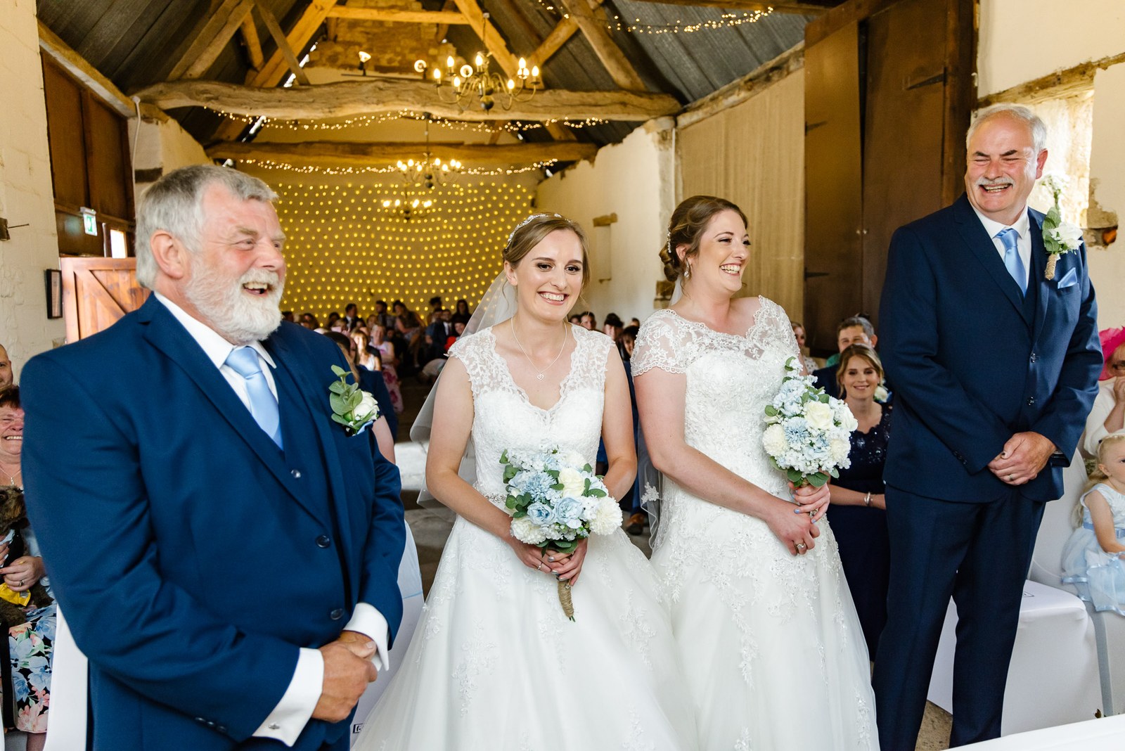 The two brides meet at the aisle, a father standing beside each