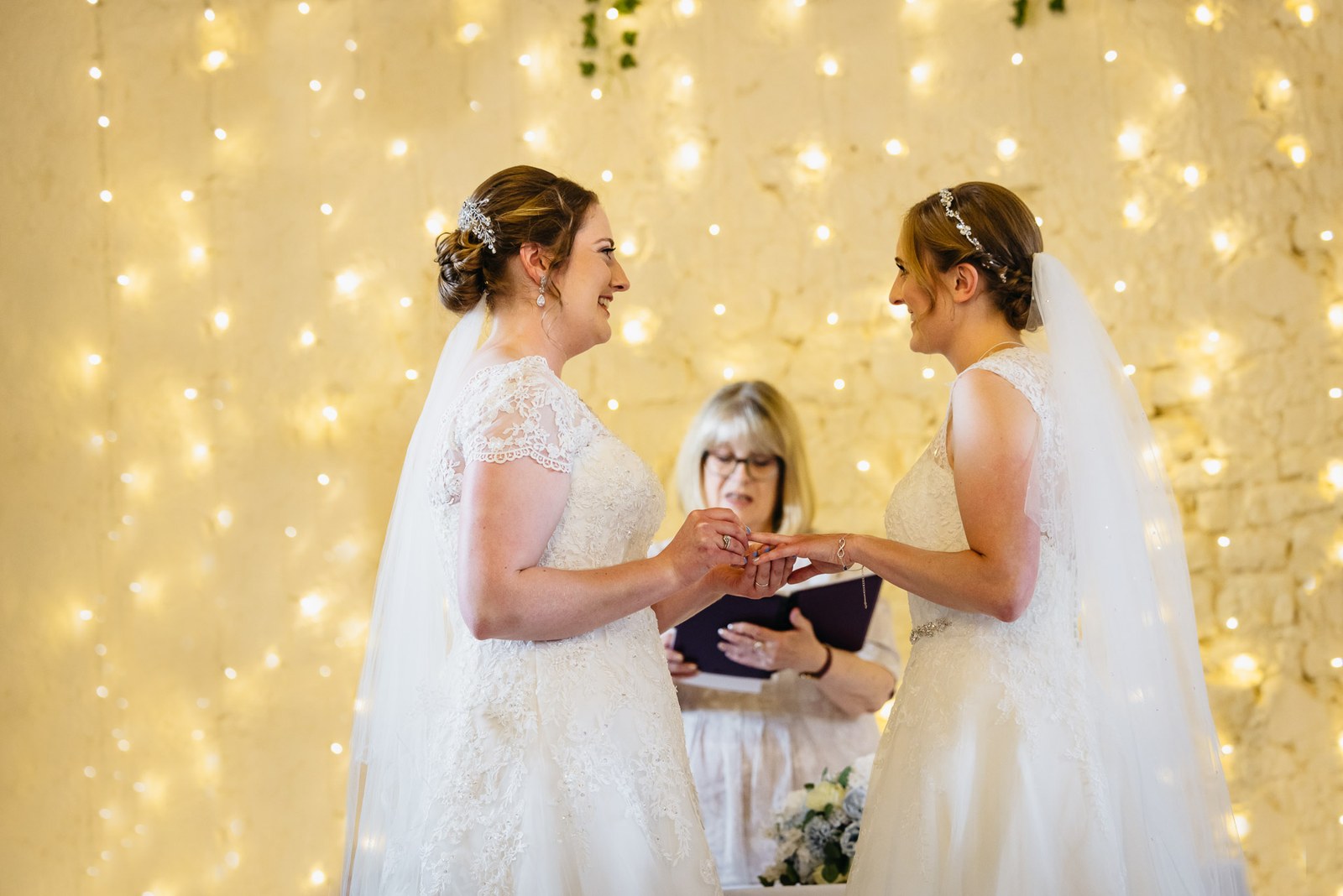 The couple exchange rings before the celebrant beneath twinkling lights