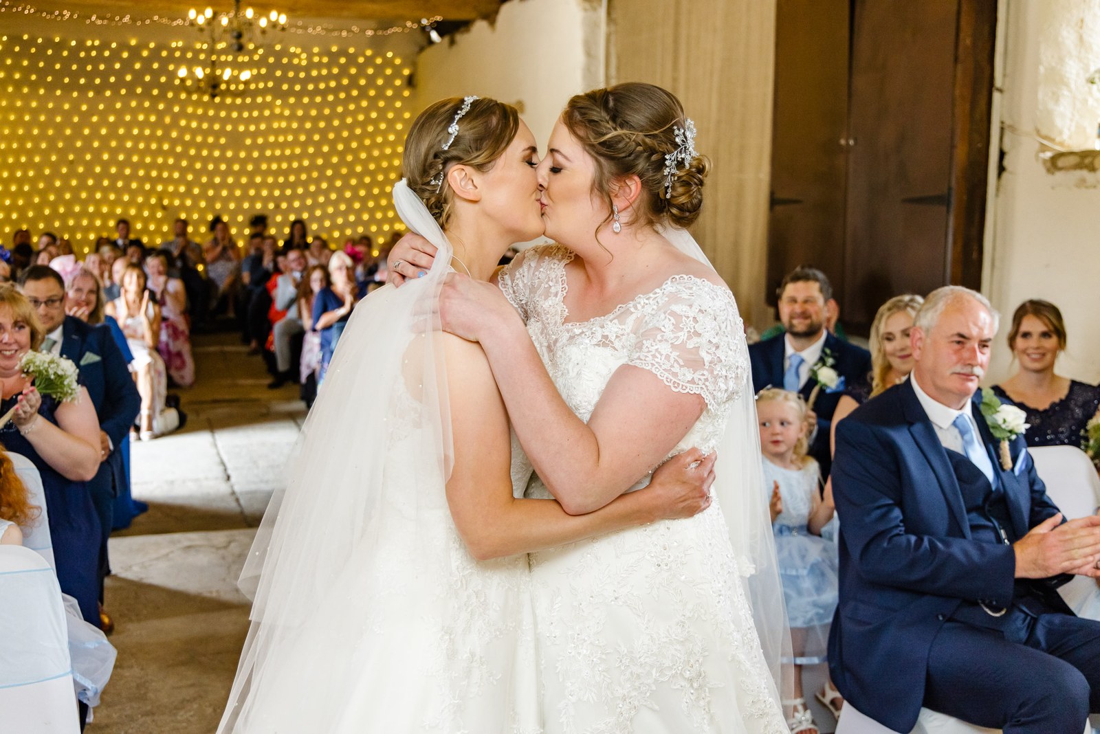 The two brides share their first kiss as married as guests applaud
