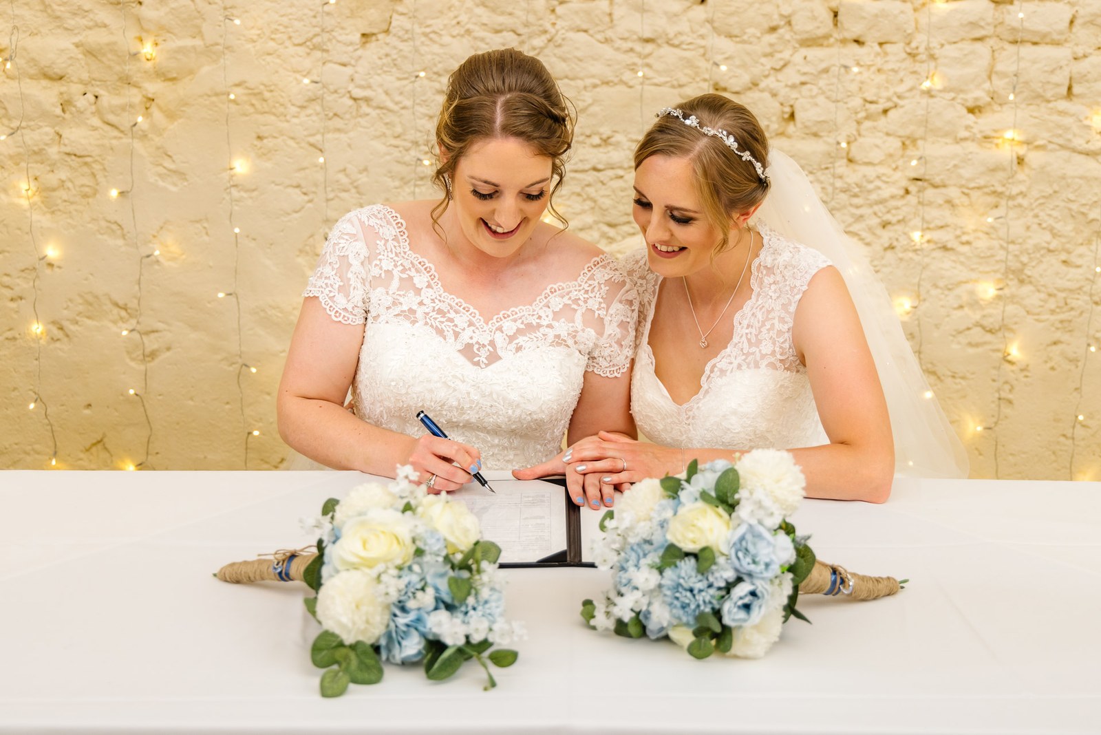 The newlyweds sign the register, bouquets resting on the table