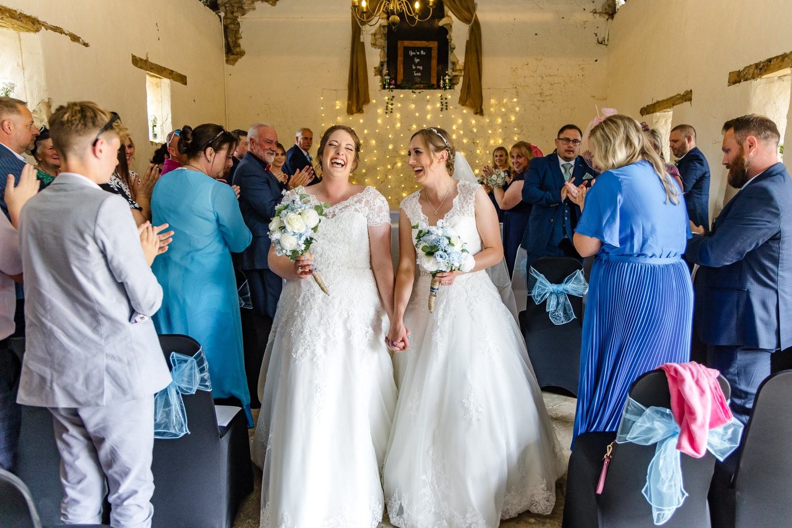 The married couple turn to cheering guests inside the fairy-lit barn