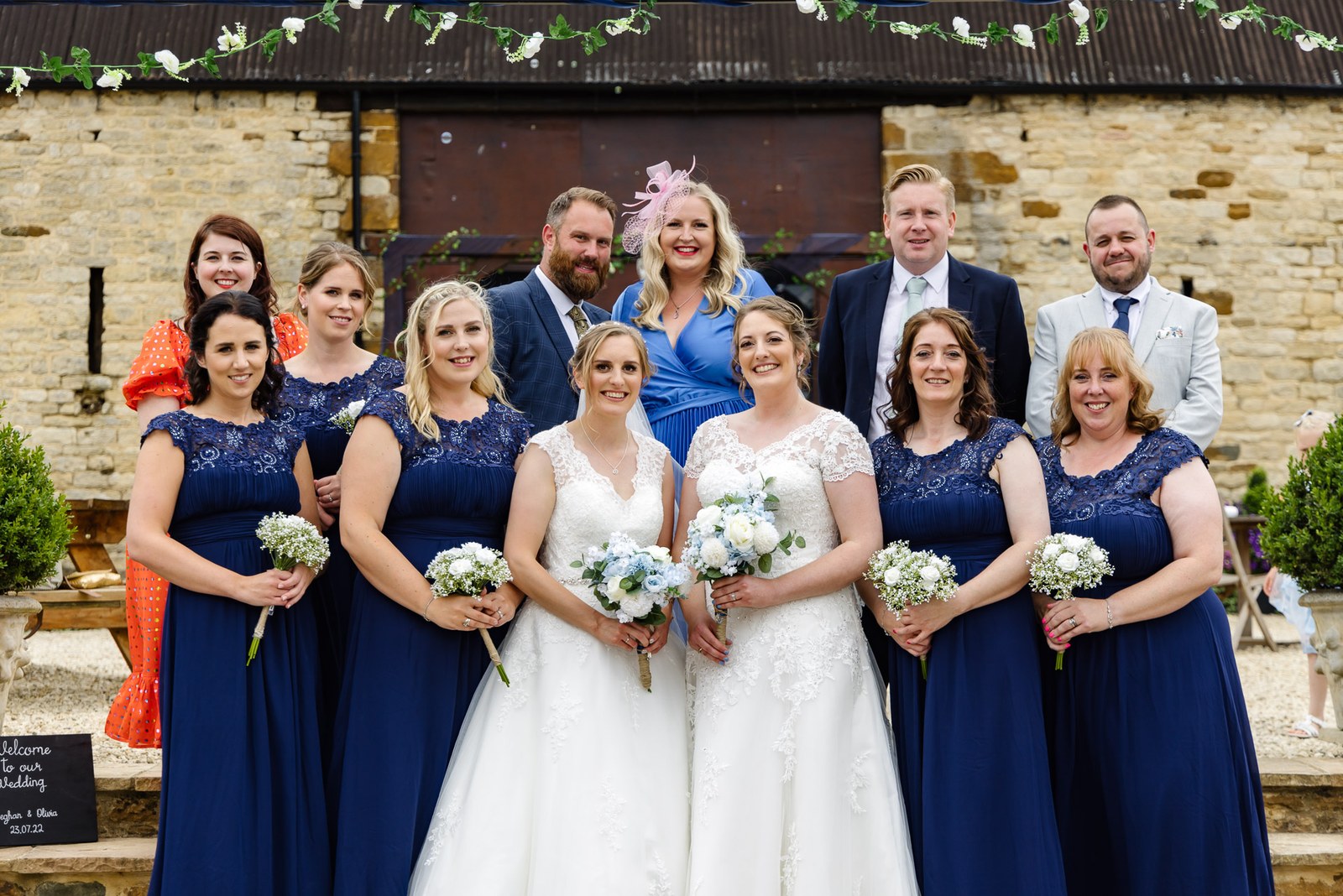 The couple with their wedding party in navy outside the Slapton Manor barn