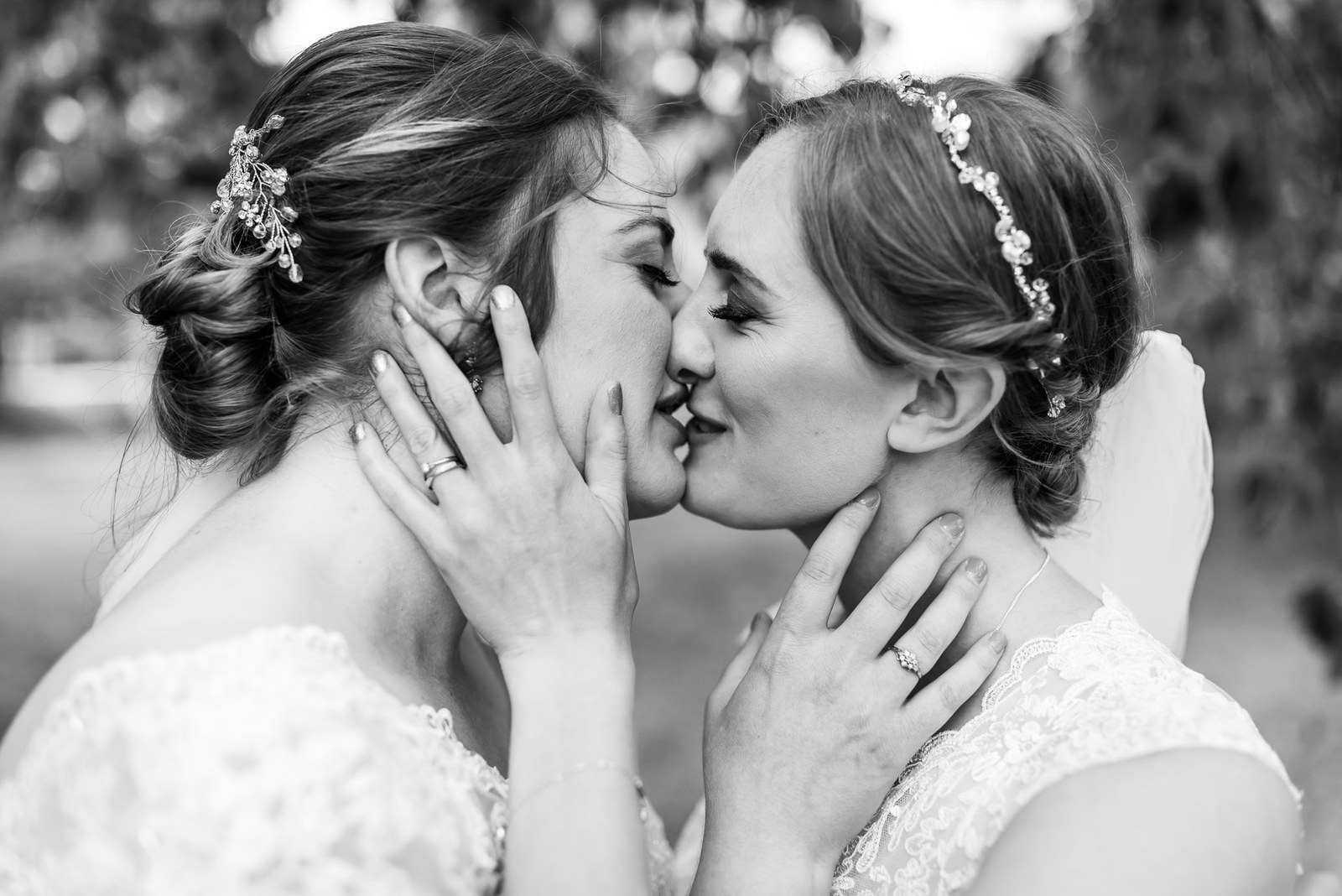Close-up black and white of the two brides kissing tenderly