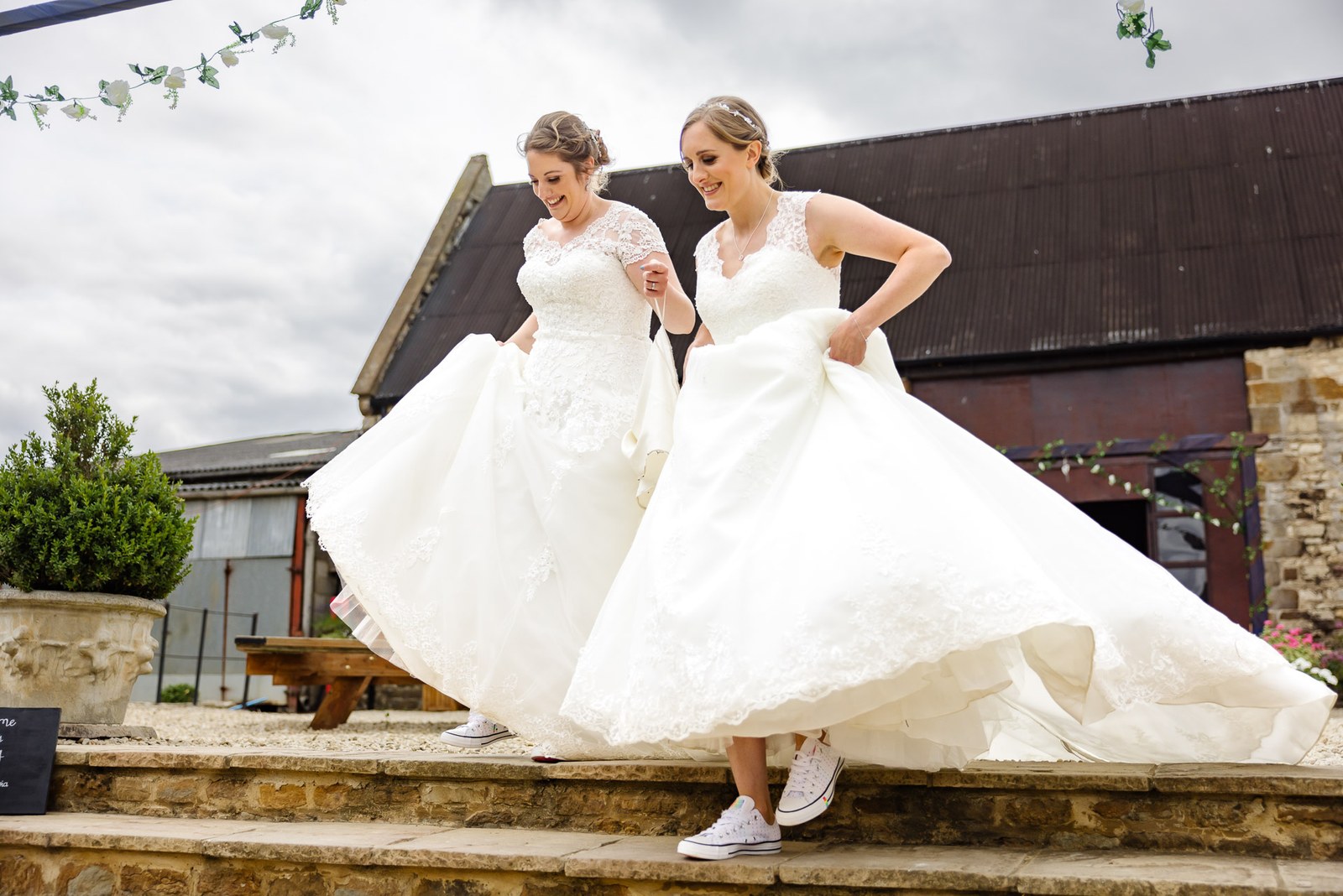 The couple lift their skirts descending the barn steps at Slapton Manor