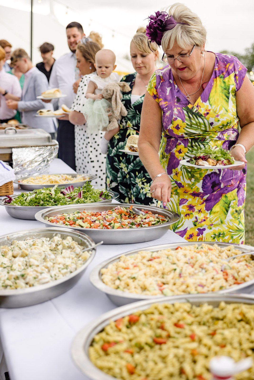 Guests help themselves to bowls of pasta salad at the buffet