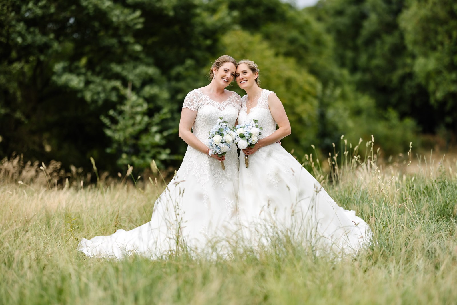 The newlyweds embrace amid long summer grasses in the manor meadow