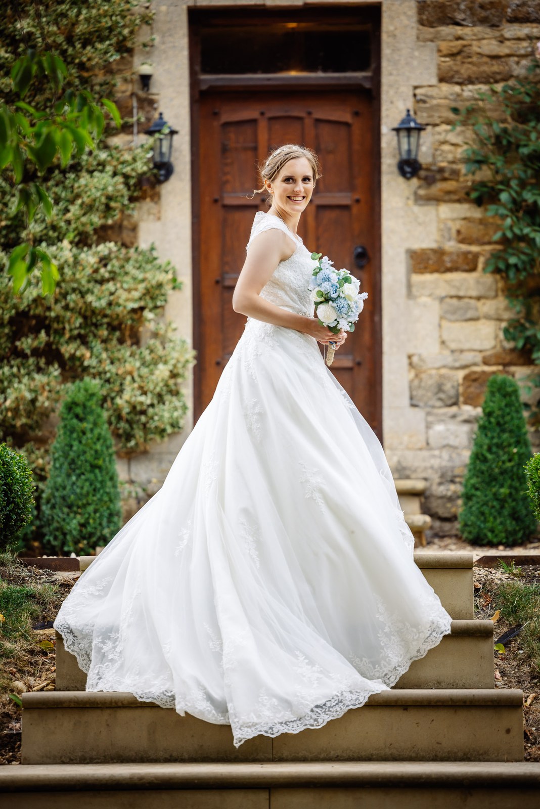 Bride twirls her full skirt on the manor's stone entrance steps