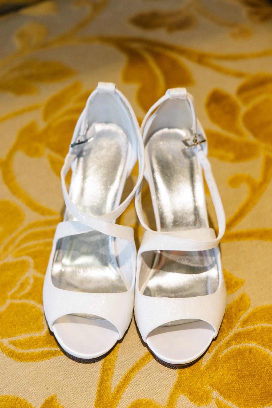 White strappy bridal sandals resting on the gold-patterned Sopwell House carpet