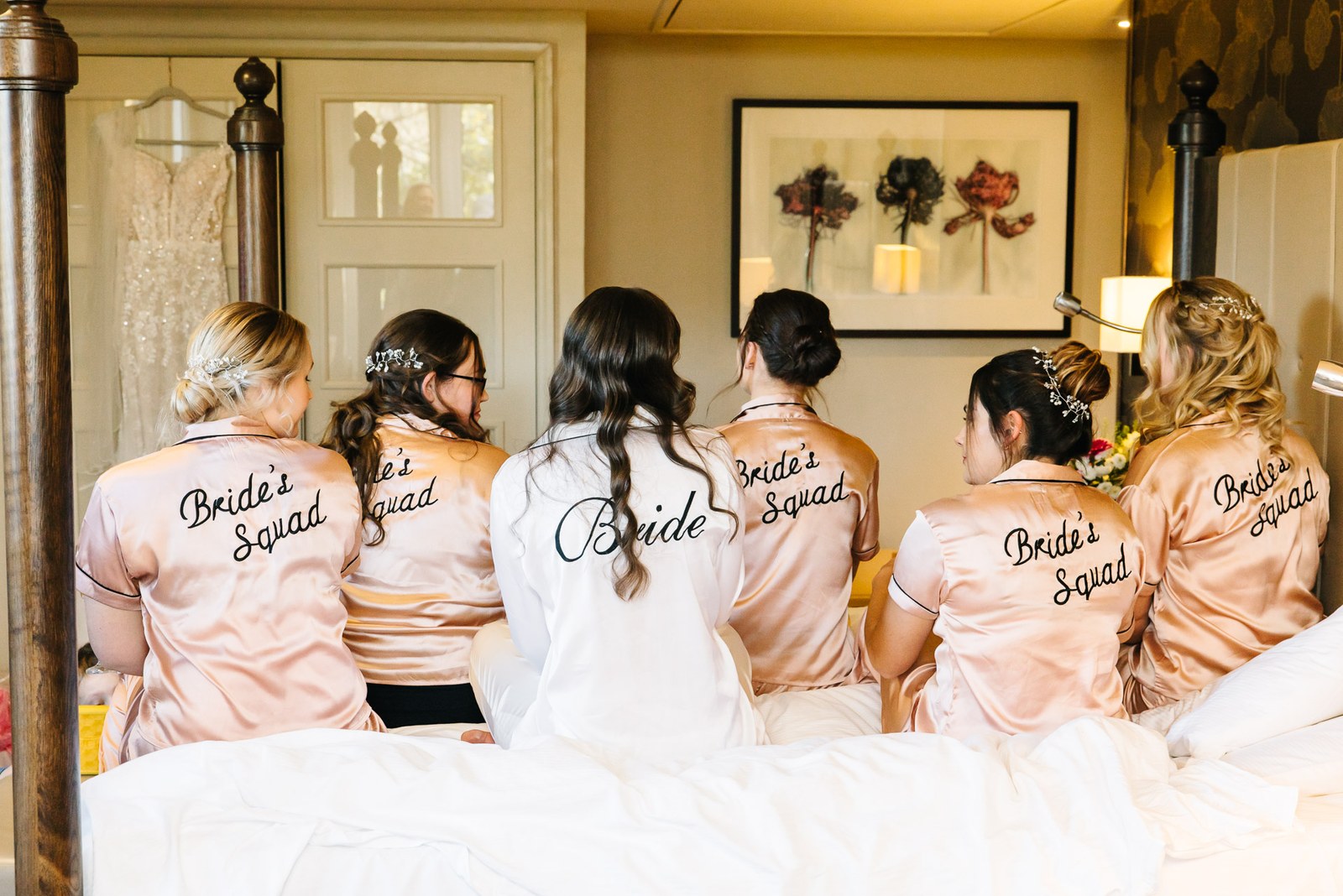 The bridal party in 'Bride' and 'Bride's Squad' pyjamas seen from behind on the bed