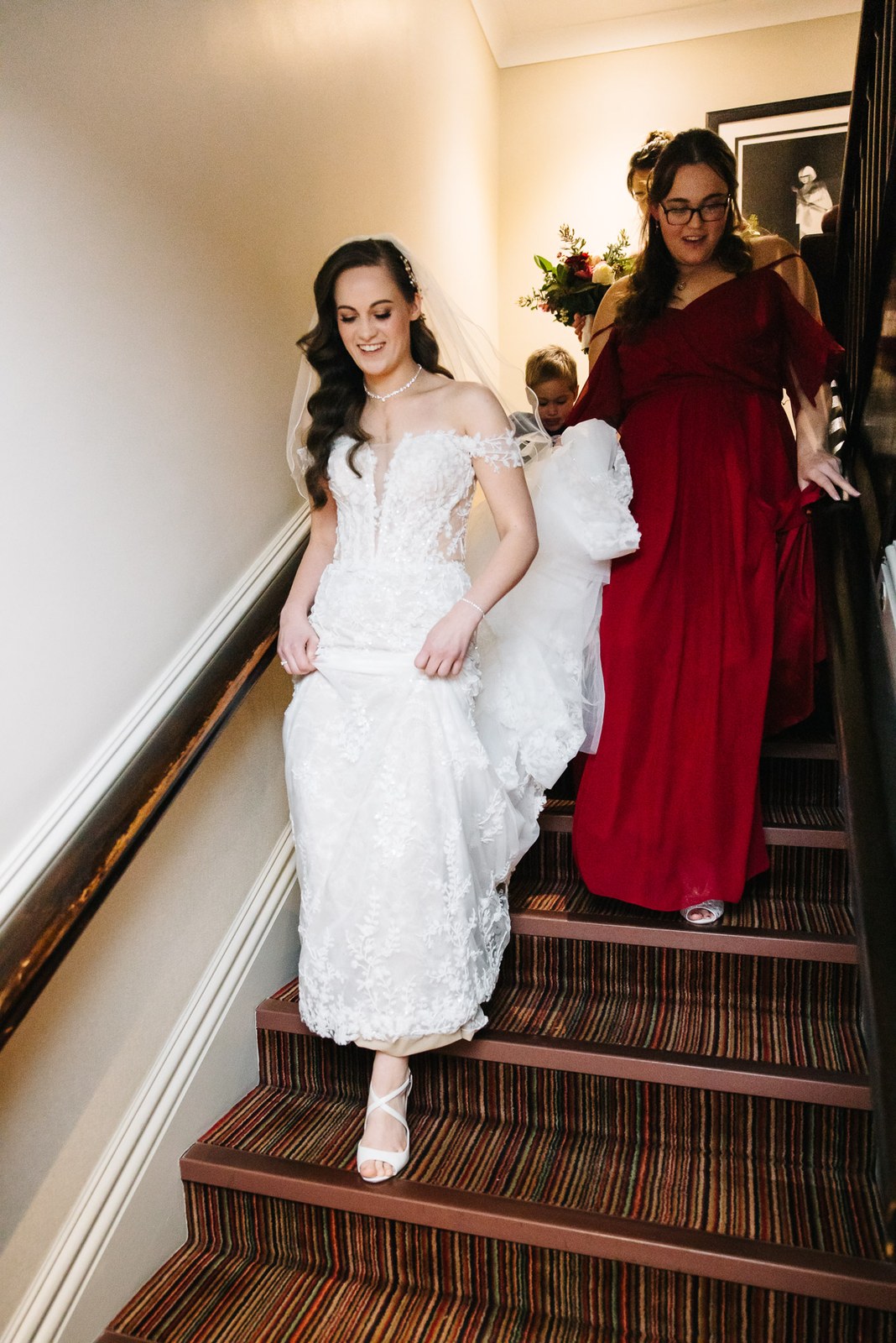 Bride descends the striped Sopwell House staircase with a bridesmaid behind