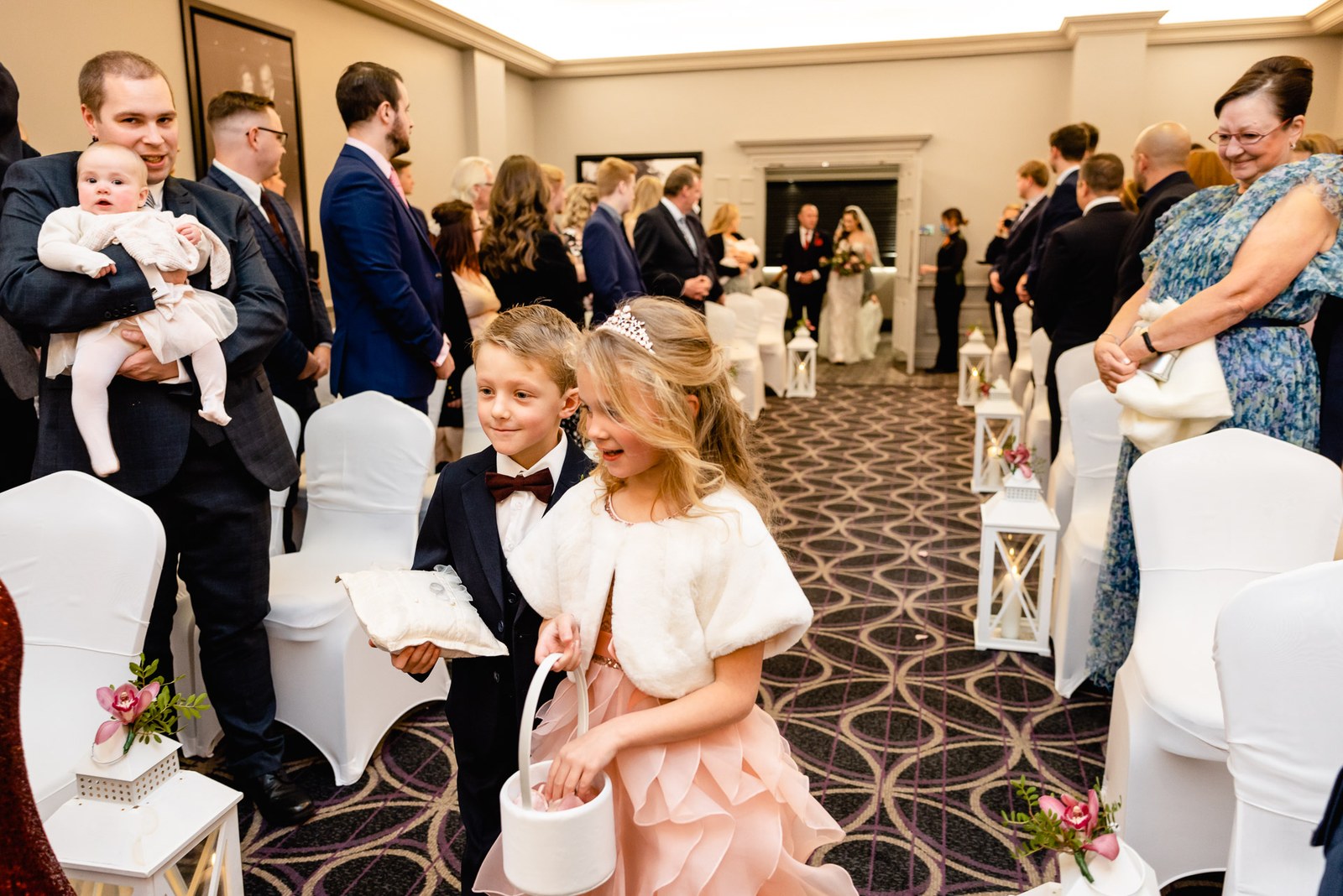 Guests stand as a flower girl with a petal basket waits by the aisle