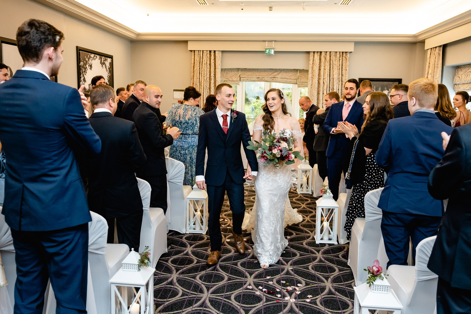Newlyweds walk back up the aisle hand in hand through their guests